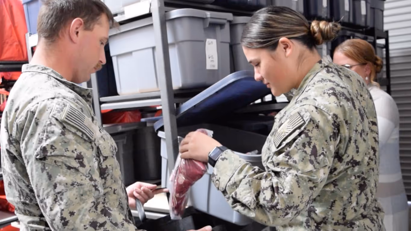 A man in a military uniform is holding a piece of meat.