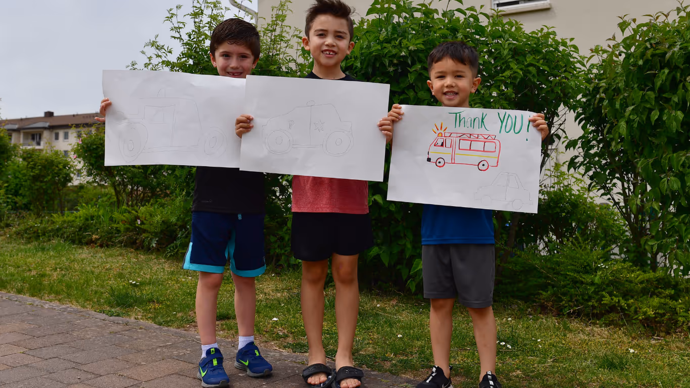 Three young boys holding up signs that say "thank you" and "I love you."
