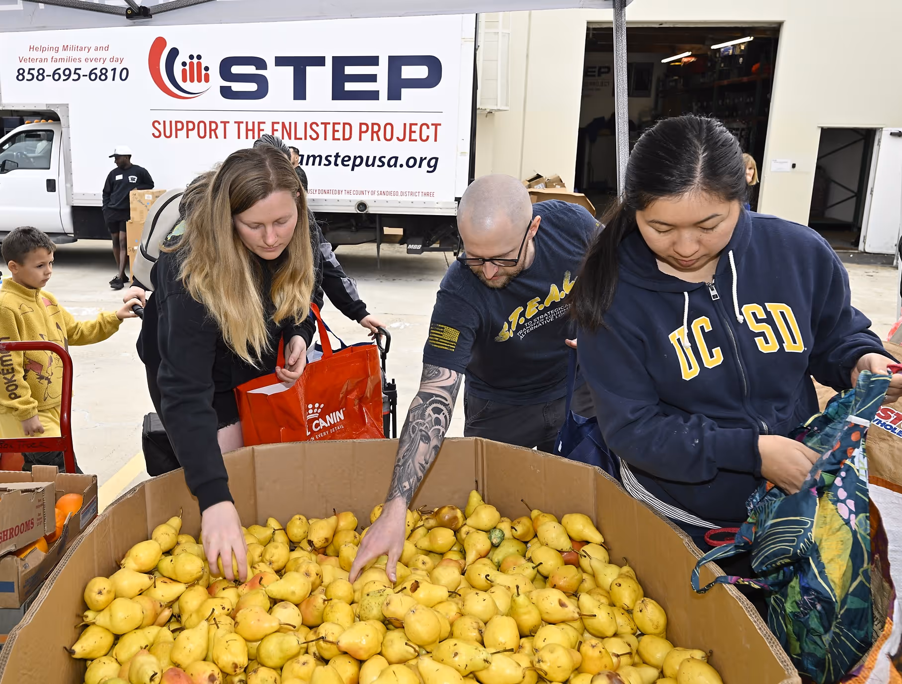A group of people are picking fruit from a box.