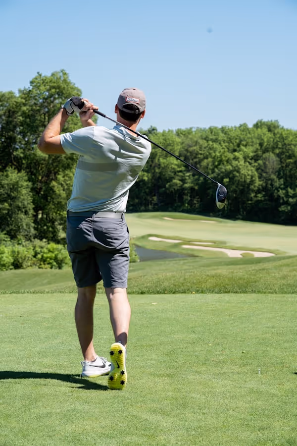 man in white t-shirt and black shorts playing golf during daytime