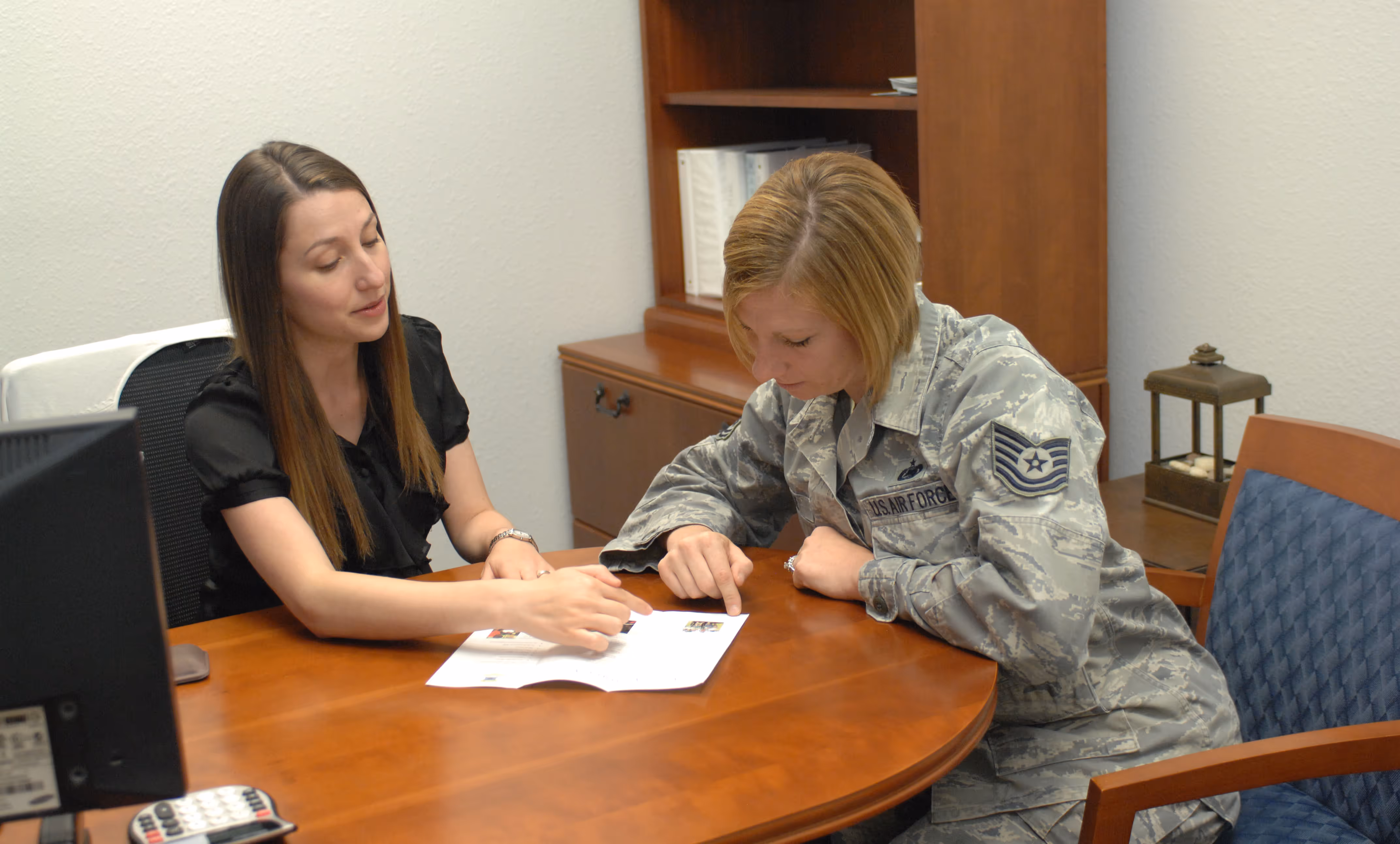 Two women sitting at a table with one of them in a military uniform.