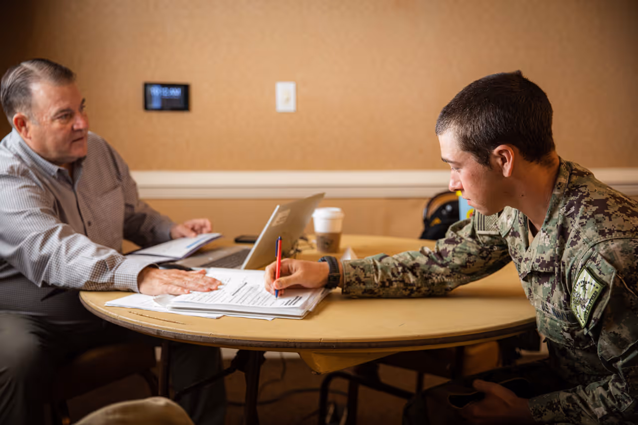 A man in a military uniform is signing a piece of paper.