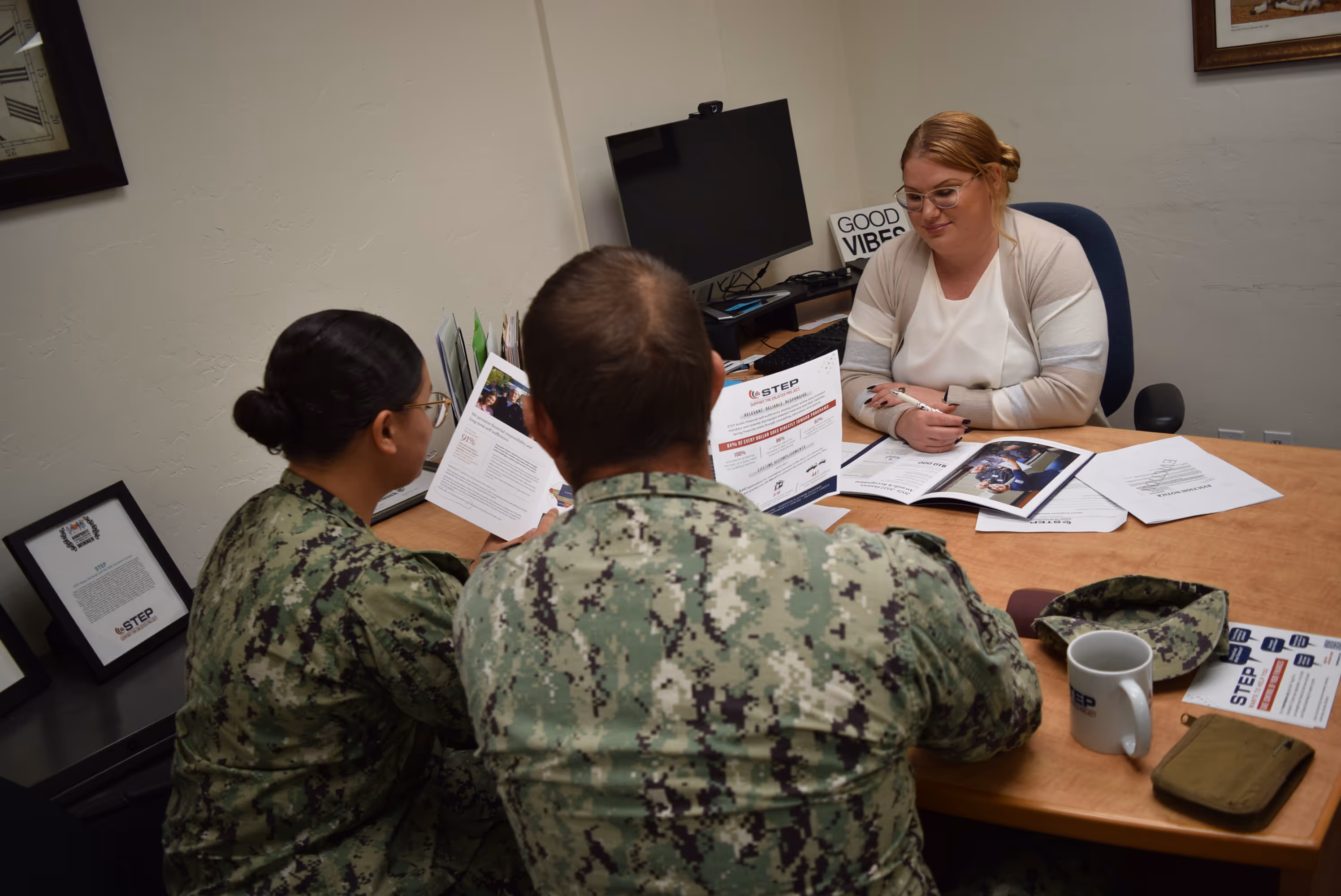 A woman and two men are sitting at a desk.