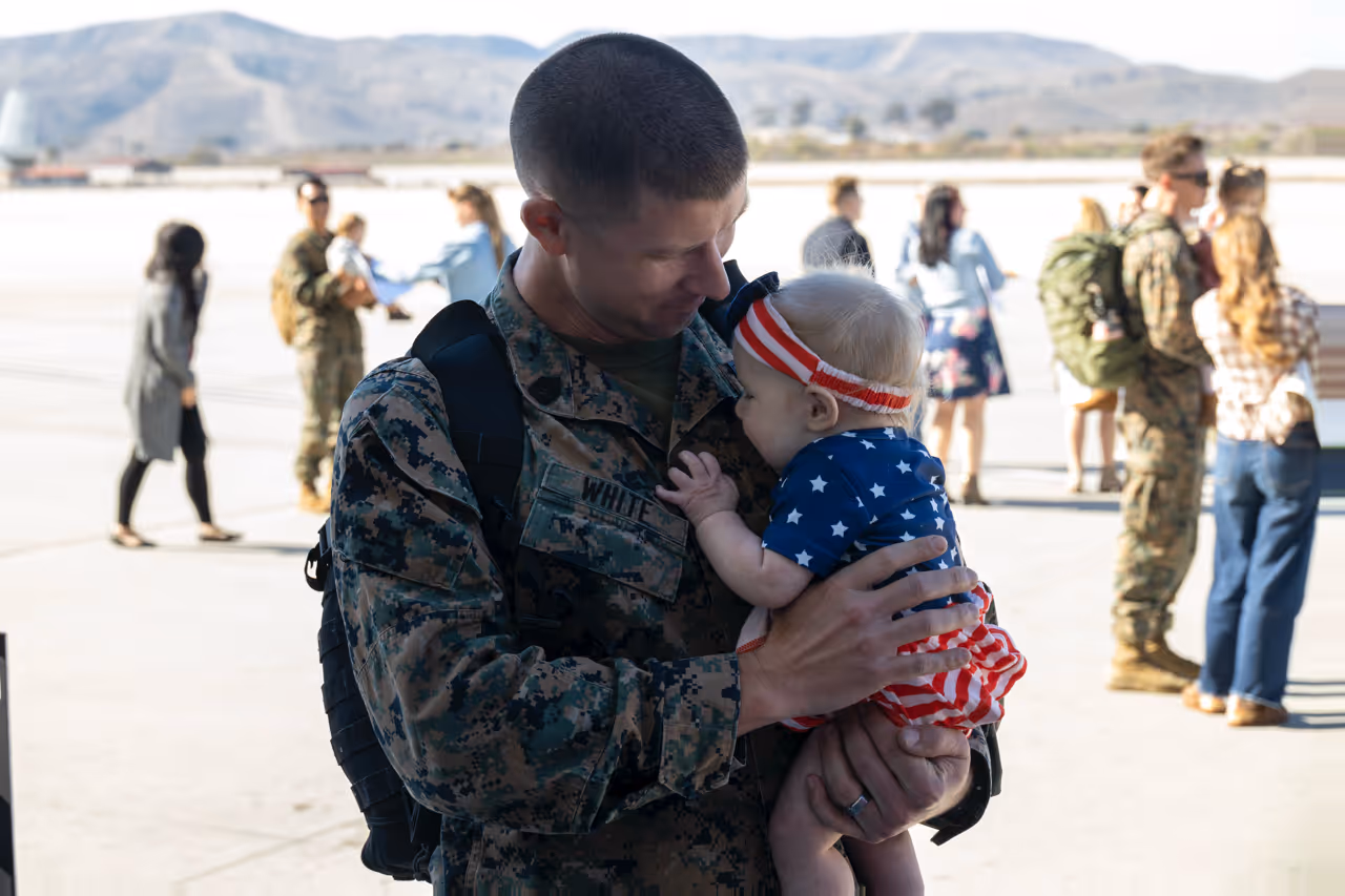 A soldier holding a baby in a patriotic outfit.