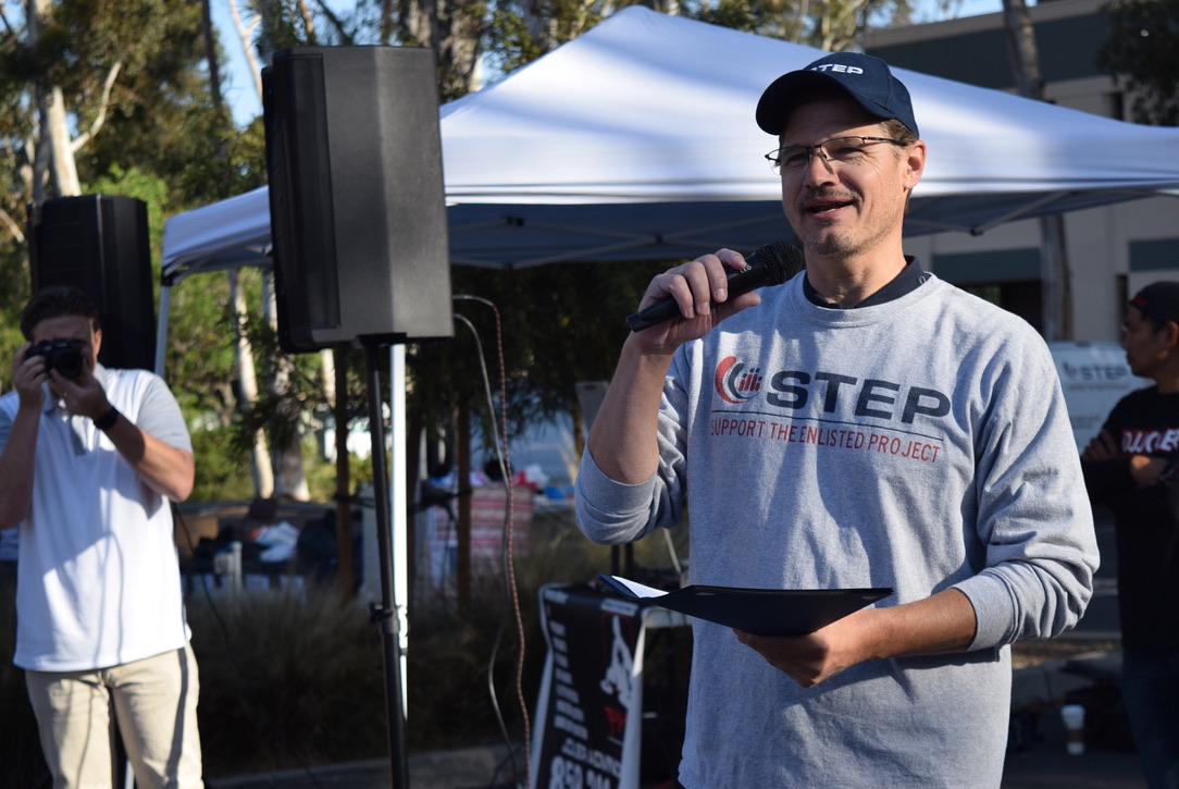 A man holding a microphone and a plaque that says "Support the Steps Project".