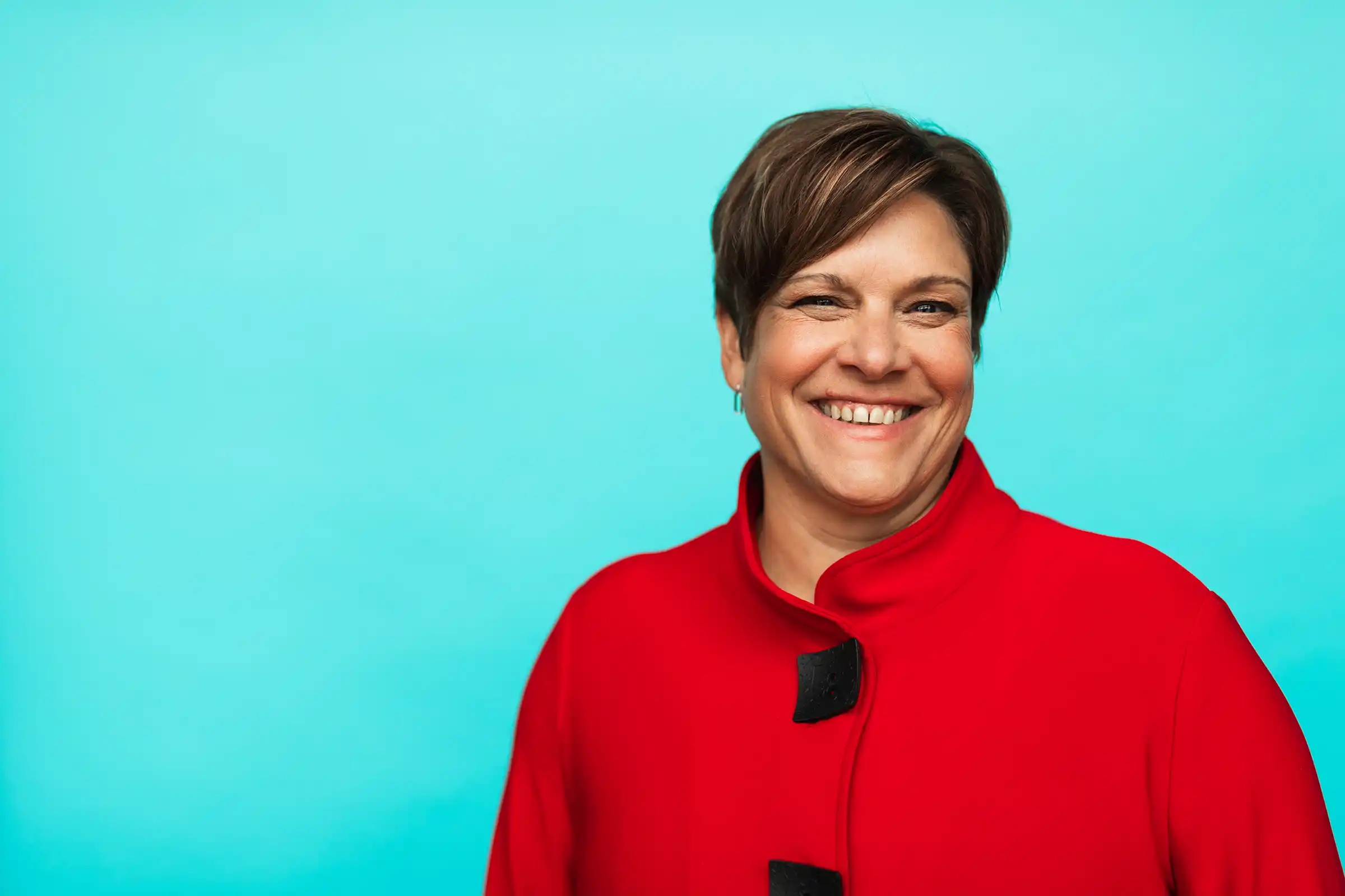 Portrait of Kathy Wulf-Tays in a red blazer, smiling.