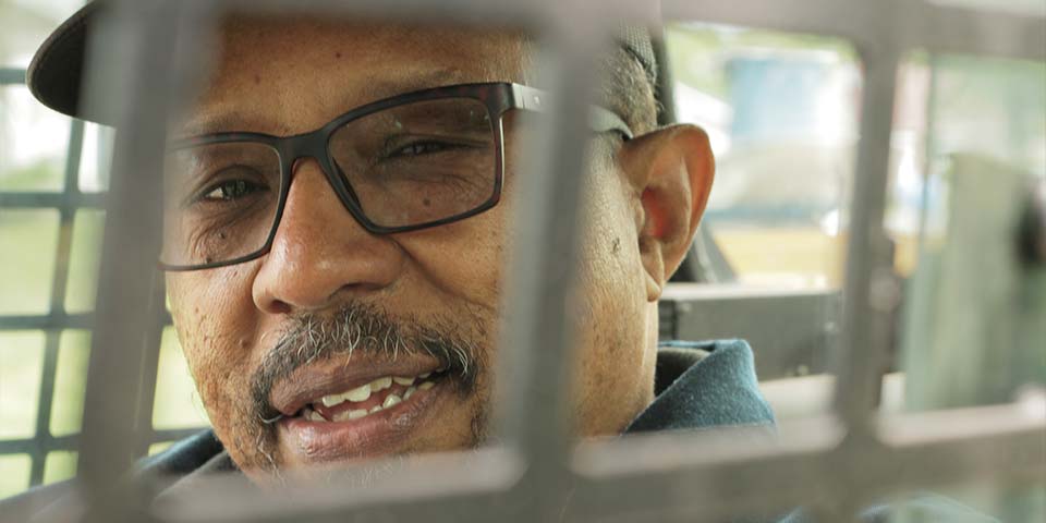 Sam's Services owner face through a bobcat cage