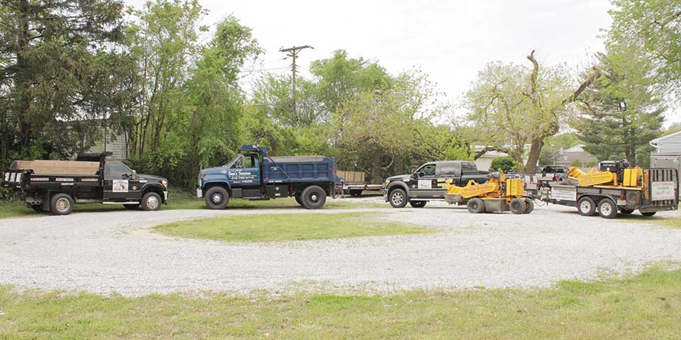 Sam's Services dump trucks, stump grinder, and bobcat machinery