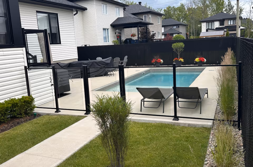 Cour avec piscine, sécurisée par une clôture en verre  et une clôture en maille.