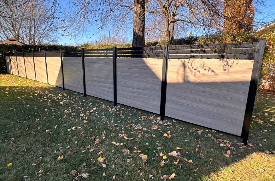 Clôture d'intimité en PVC gris pâle avec une section supérieure ajourée, installée dans une cour en automne.
