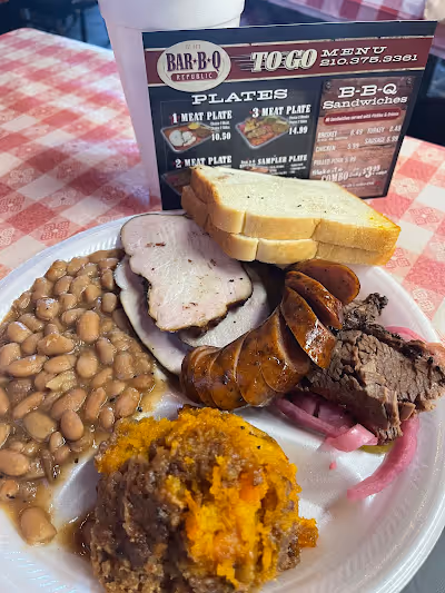 A plate featuring a serving of beans, meat, and slices of bread arranged neatly.