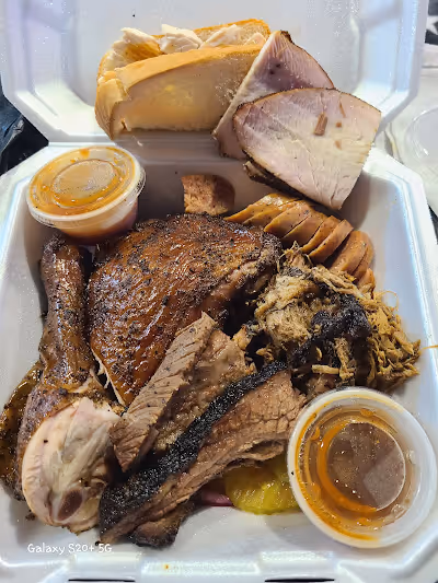 A white container filled with assorted meat, bread, and condiments arranged for a meal.