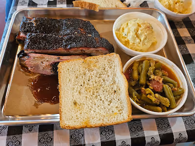  A tray featuring barbecue, green beans, and a side dish, arranged neatly for a meal presentation.
