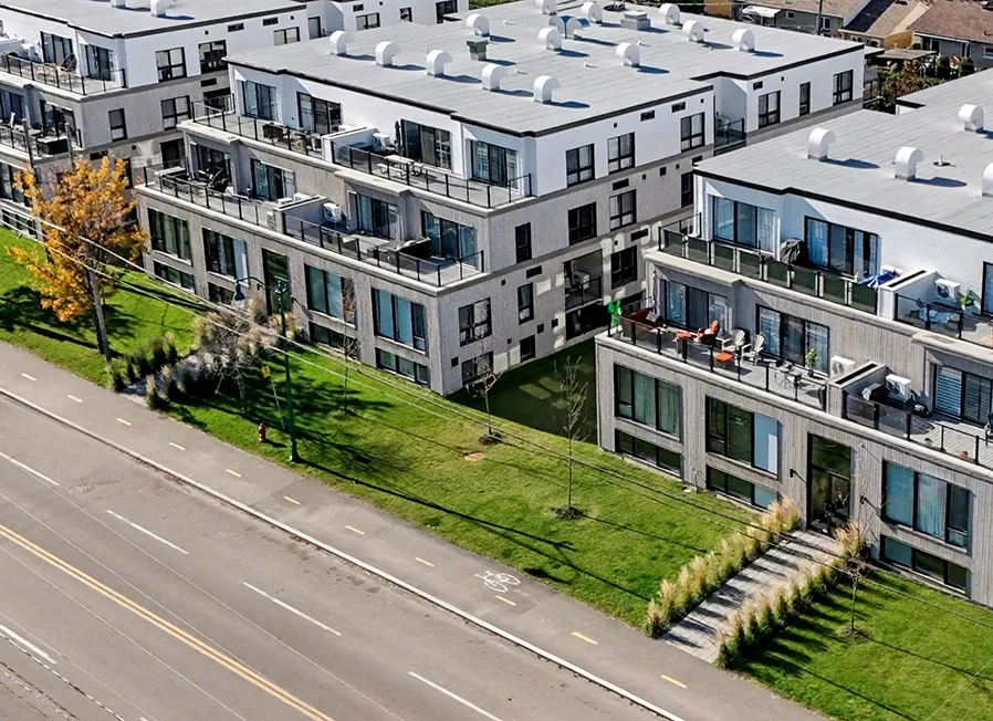 Modern residential buildings with balconies overlooking a green lawn and a road with a marked bike lane.