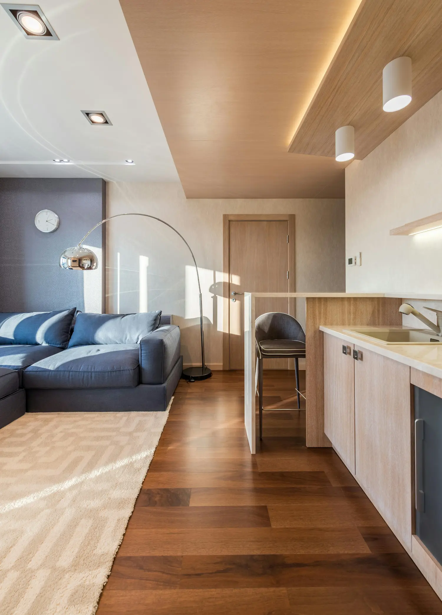 Modern open-plan living room with elegant wooden kitchen and natural wood flooring