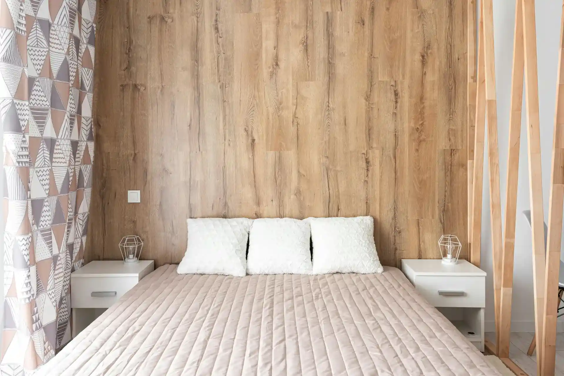 Minimalist bedroom design with wood accent wall, neutral bedding, and modern bedside tables
