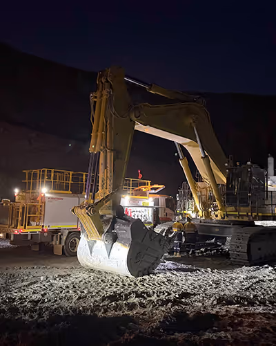 Heavy-duty mine haul truck parked on red soil at dusk
