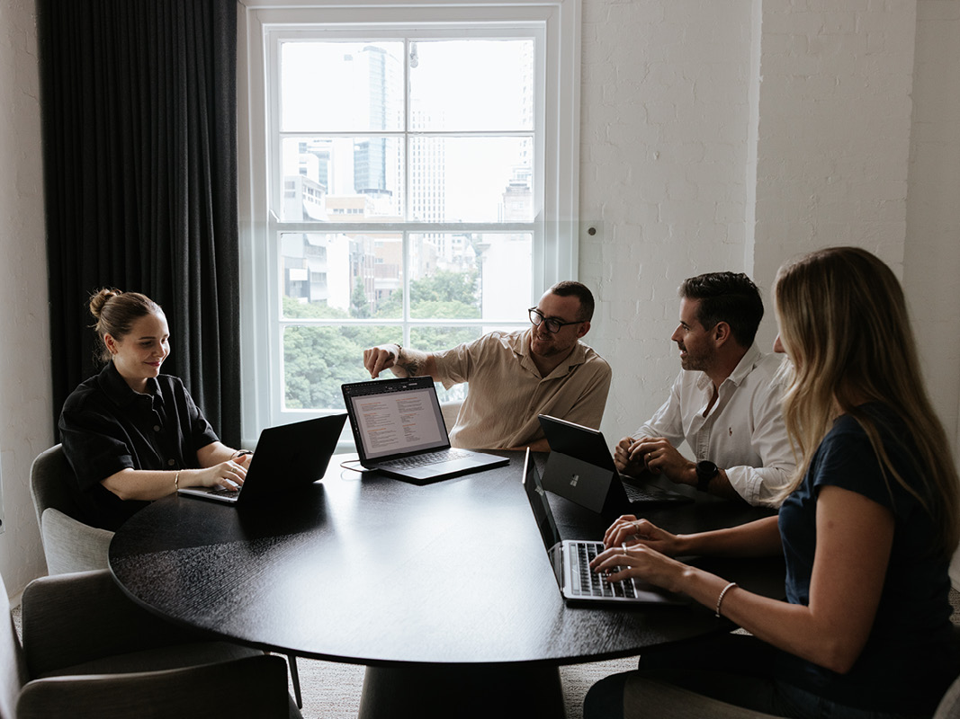 Team meeting around a table with laptops in a bright office