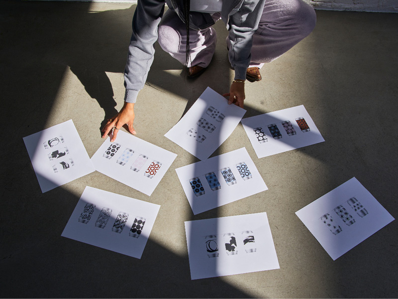Person laying out printed design sheets on a concrete floor