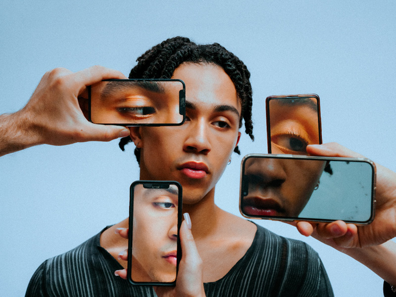 Person framed by phones showing close-ups of eyes and lips