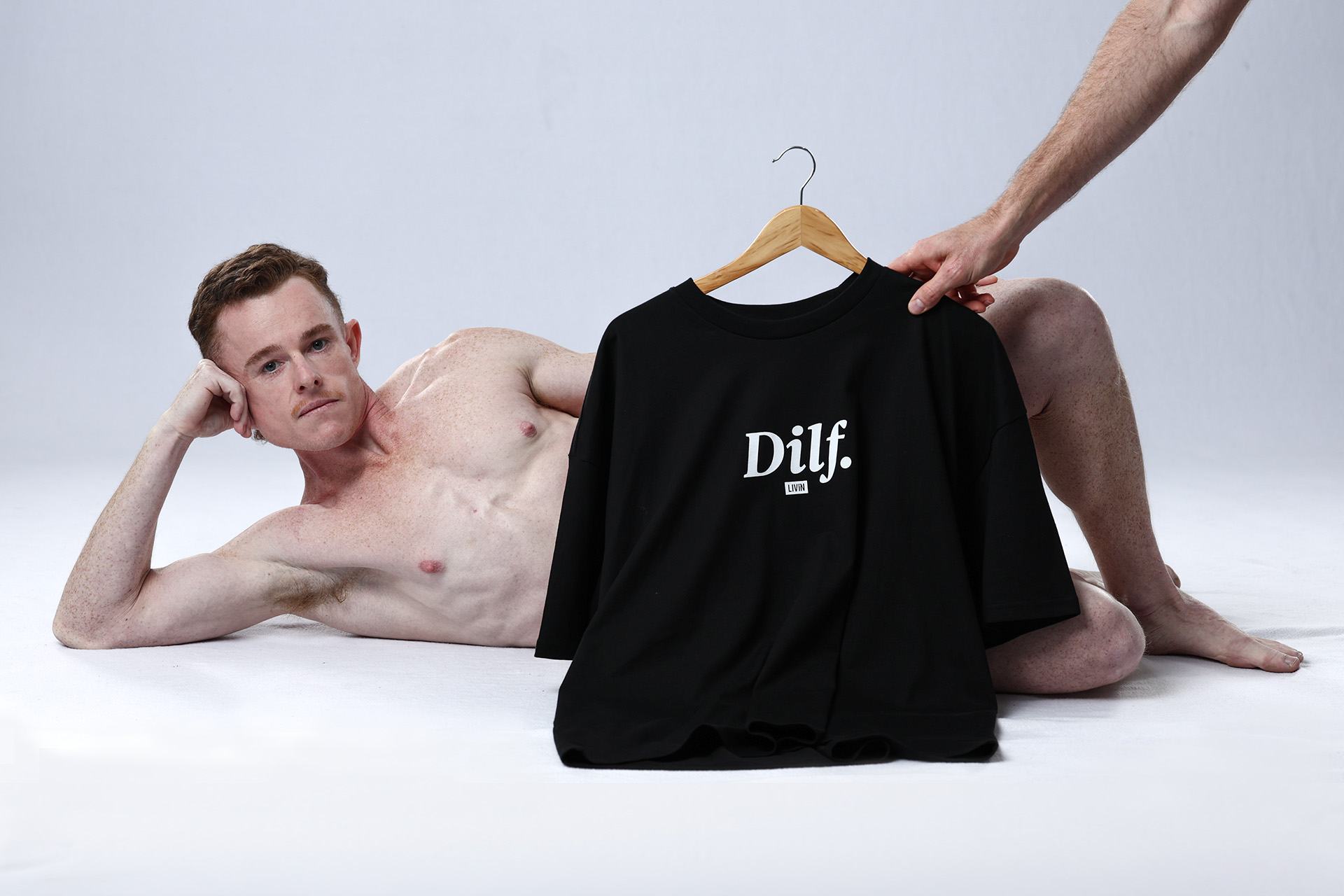 Man posing with a black LIVIN Dilf. T-shirt on a hanger for the DILF campaign