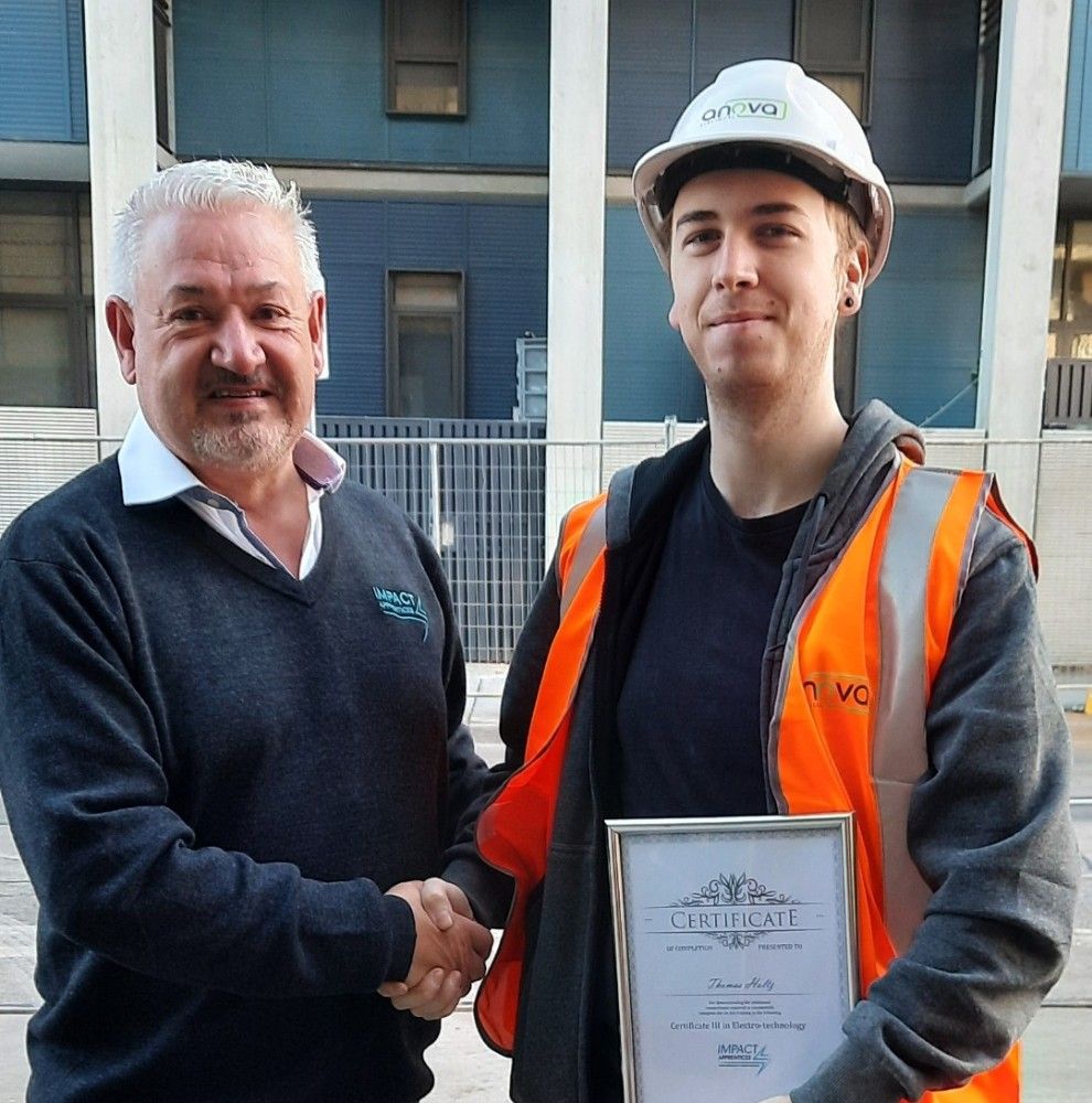 An image of Ian Theobald shaking hands with one of our electrical apprentice while handing over their apprenticeship completion certificate