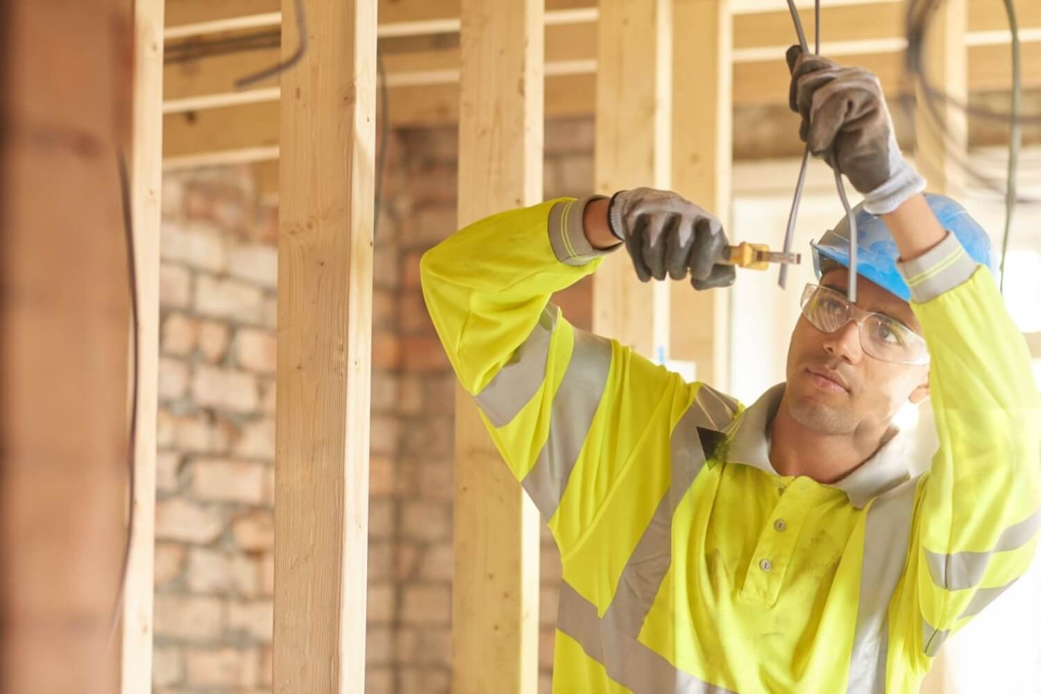 A young male carpenter clipping electrical wires on a first fix
