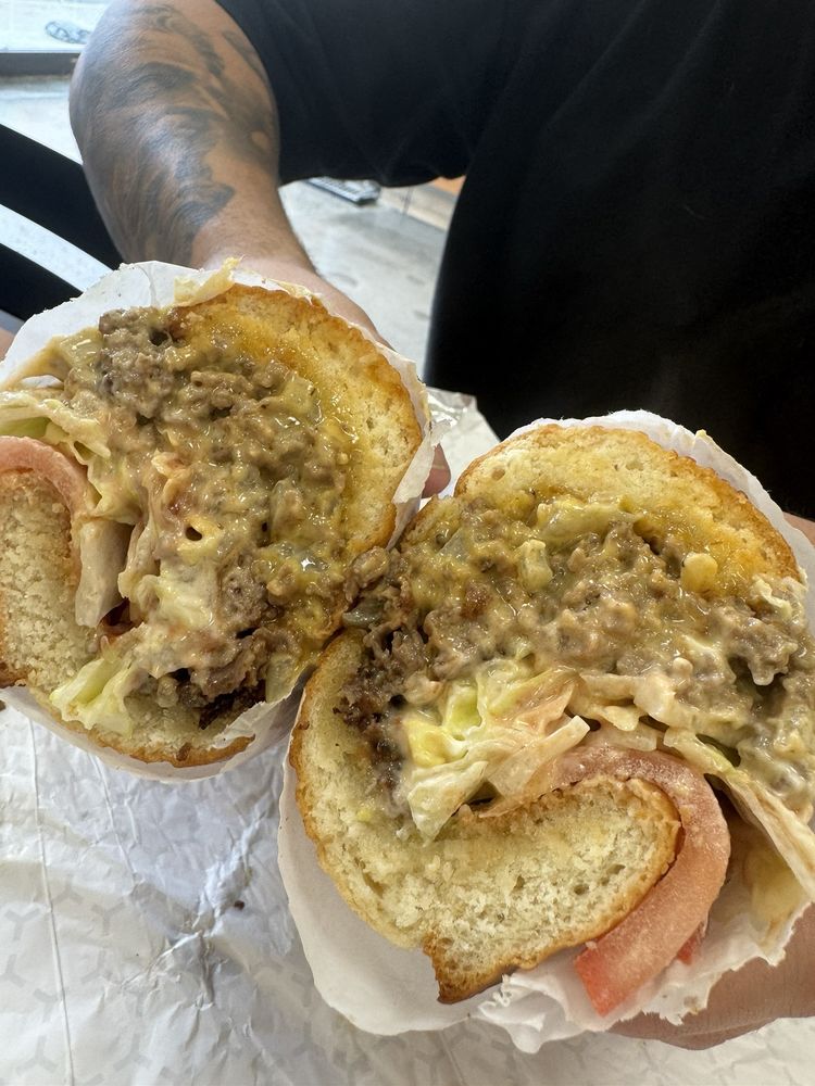 a diner holds a chopped cheese sandwich split into, focusing on the melted cheese and juicy meat.