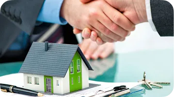 An image of A handshake above a miniature house, symbolizing a real estate transaction.