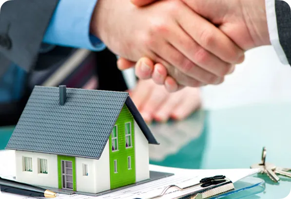 An image of a handshake over a miniature house, representing a real estate deal.