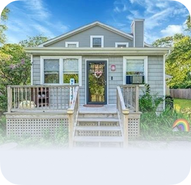 An image of a small gray house in Mastic Beach with front steps and a porch.