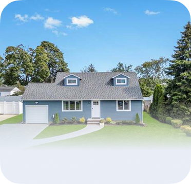 An image of a blue house in Hicksville with dormer windows and attached garage.
