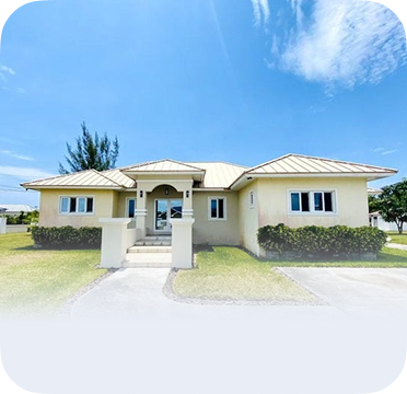 An image of a single-story light yellow house in Freeport with a metal roof and front driveway.