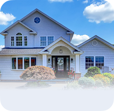 An image of a two-story house in Massapequa with arched entryway and front garden.