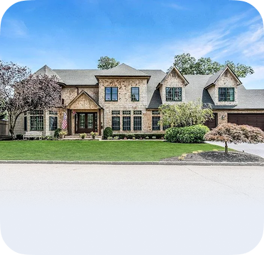 An image of a large stone house in Blue Point with gabled roof and landscaped lawn