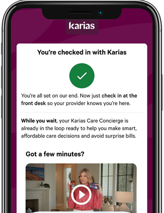 Smartphone screen showing confirmation message for Karias check-in with a green checkmark, instructions to check in at the front desk, and a video thumbnail with a woman holding a card.