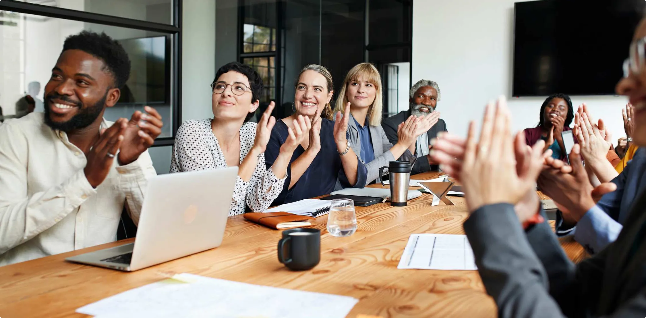 A group of people sitting at a meeting clapping