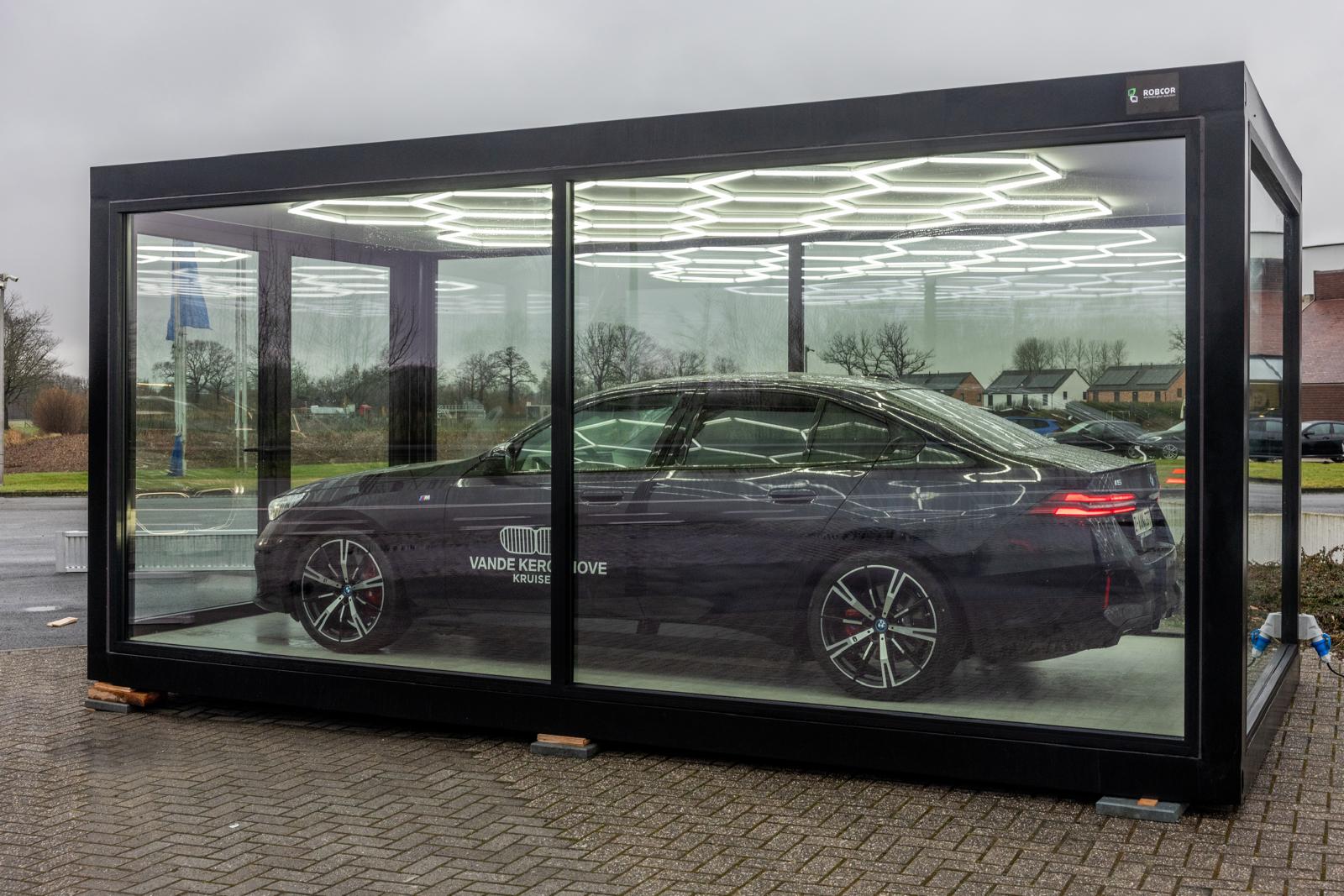 Een modulaire unit van ROBCOR met glazen wanden en hexagonale LED-verlichtingspanelen. In de unit staat een auto geplaatst. 