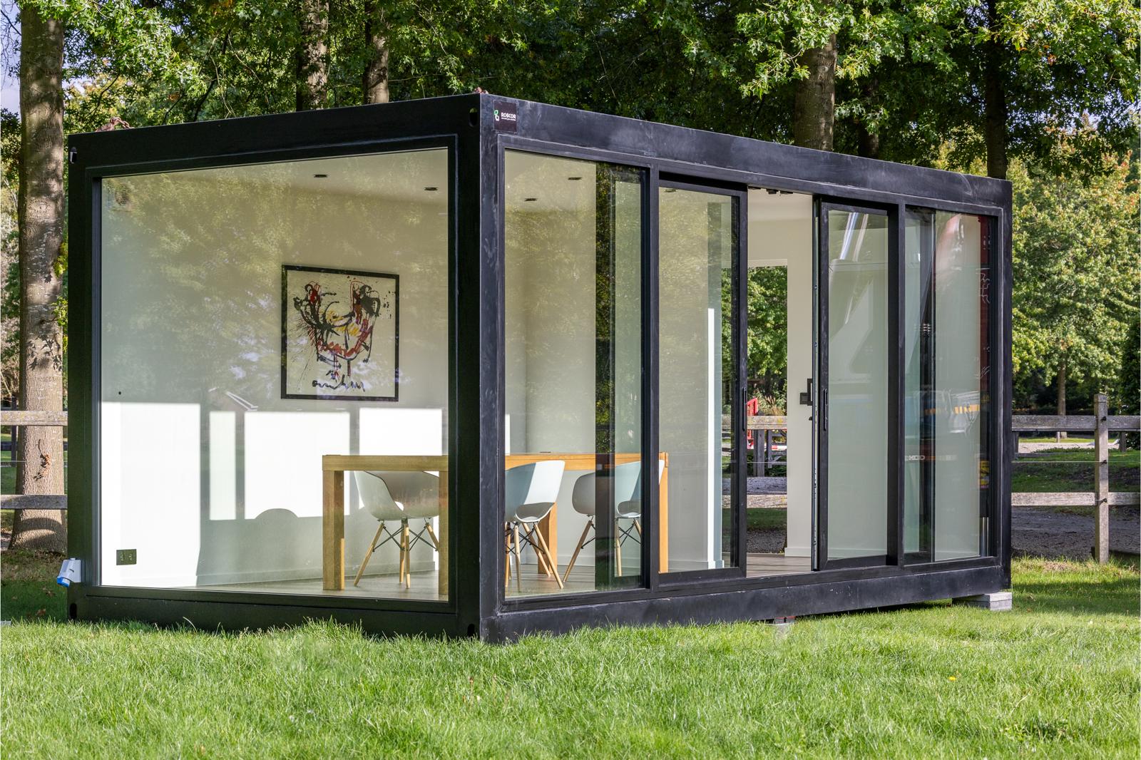 Een unit met glazen wanden en een tafel, ontworpen als multifunctionele unit door ROBCOR.