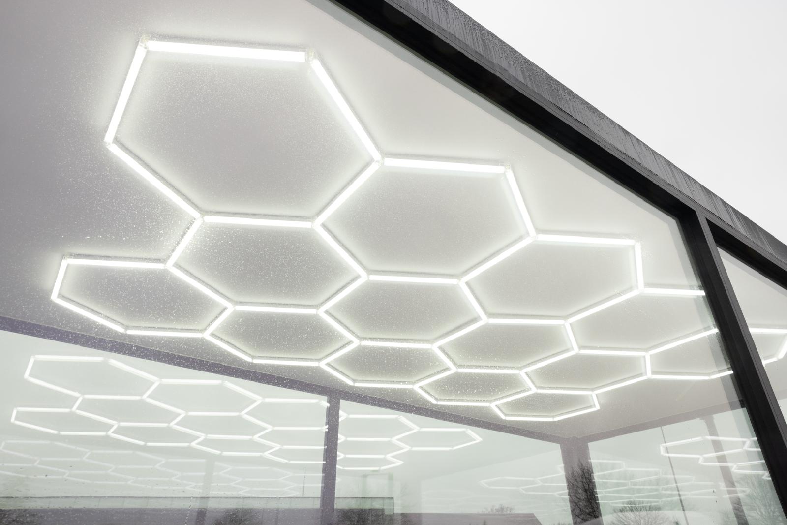 Een modern interieur met hexagonale LED-verlichtingspanelen op de plafond en wand, creërend een helder en strak design.