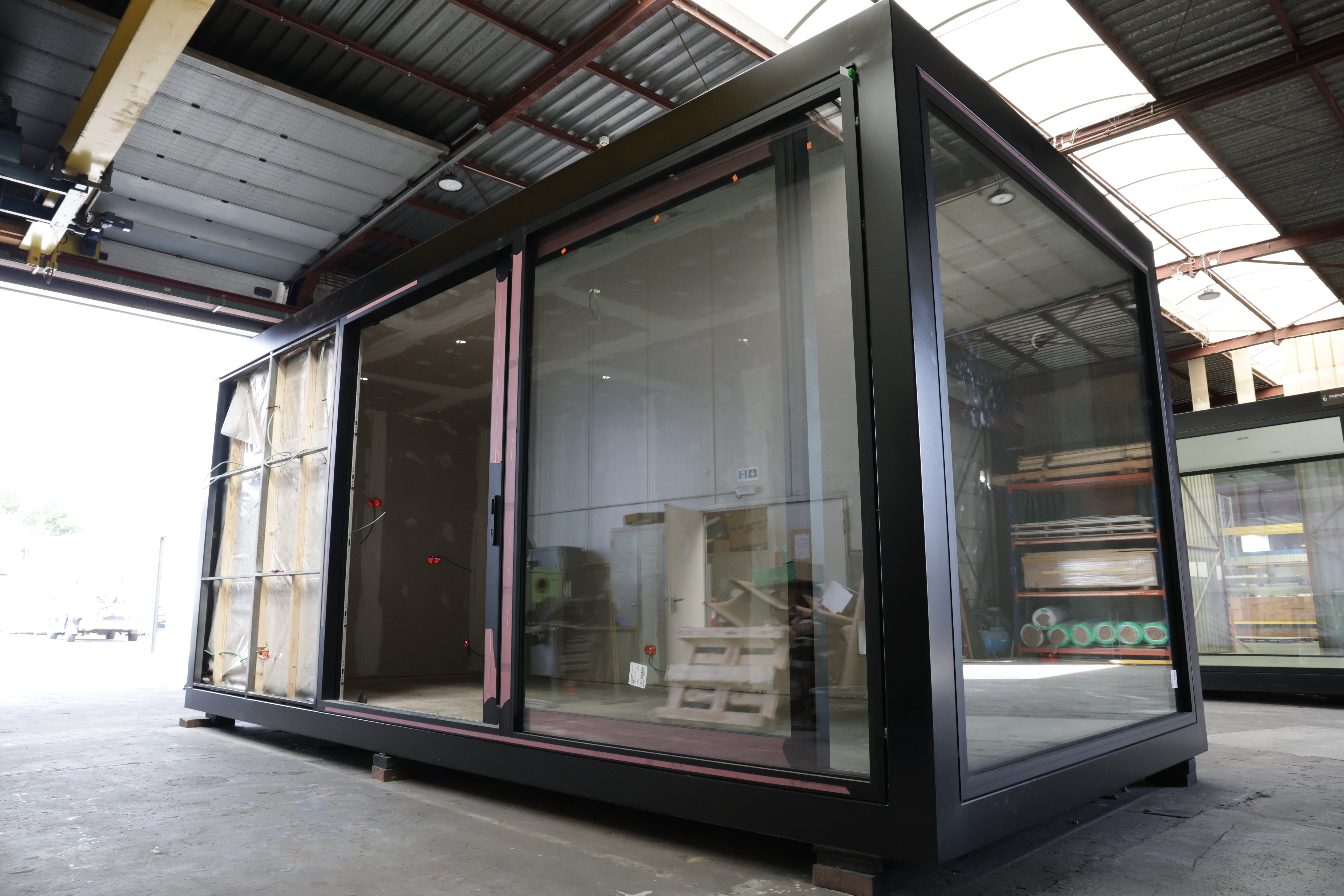 Een modulaire unit in opbouw in een industriële omgeving, met metalen structuren.