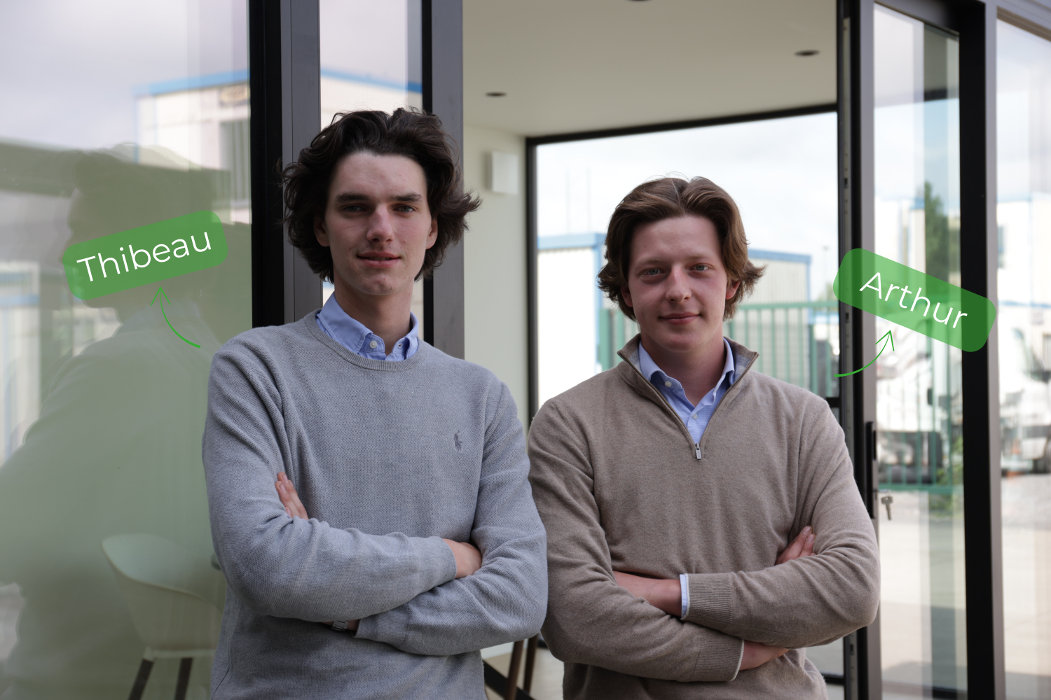 Twee jonge mannen staan zelfverzekerd met gekruiste armen in een modern kantoor. Ze dragen lichte truien en overhemden. Namen “Thibeau” en “Arthur” zijn aangegeven.
