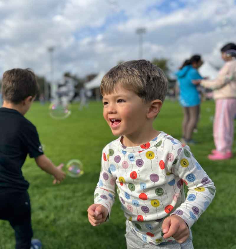 Young boy running around with bubbles at a Victoria park