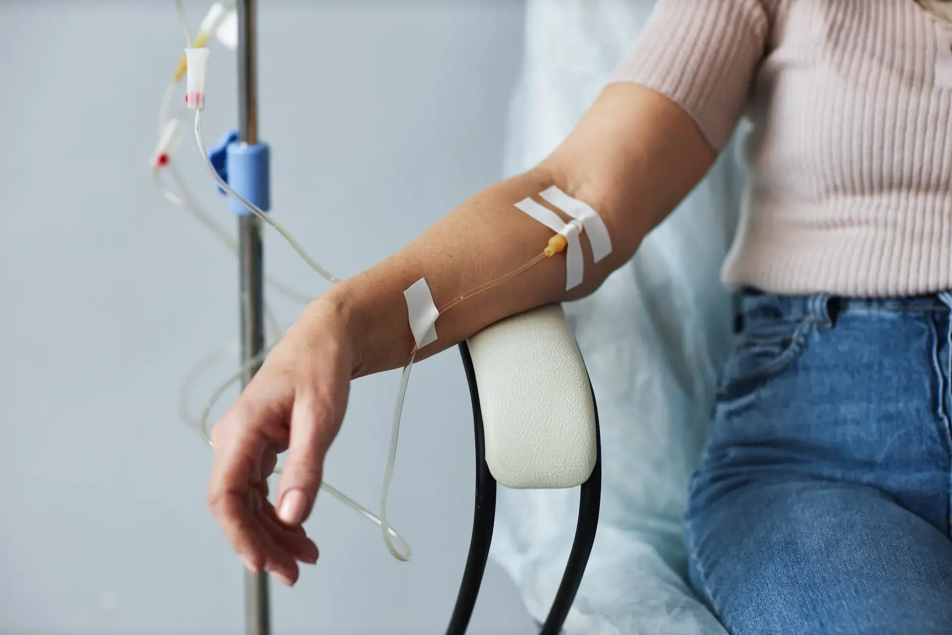 Woman receiving IV therapy treatment with IV line inserted in arm in medical setting