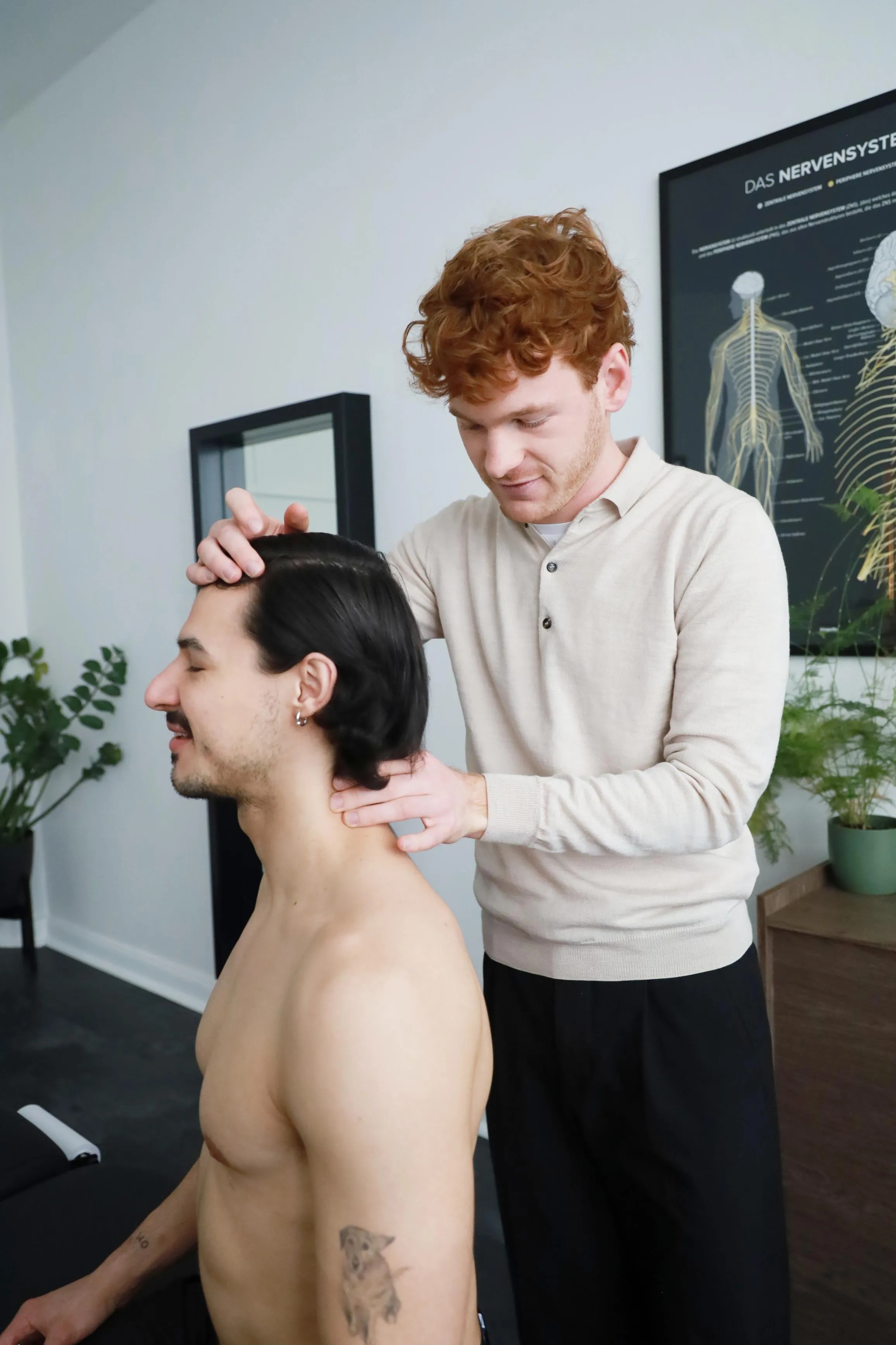 Ein Chiropraktiker behandelt einen sitzenden Patienten, indem er dessen Nacken massiert.