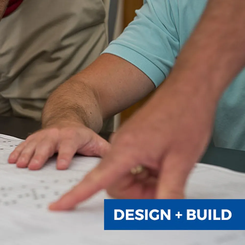 Two people reviewing architectural plans with one person pointing at the blueprints.