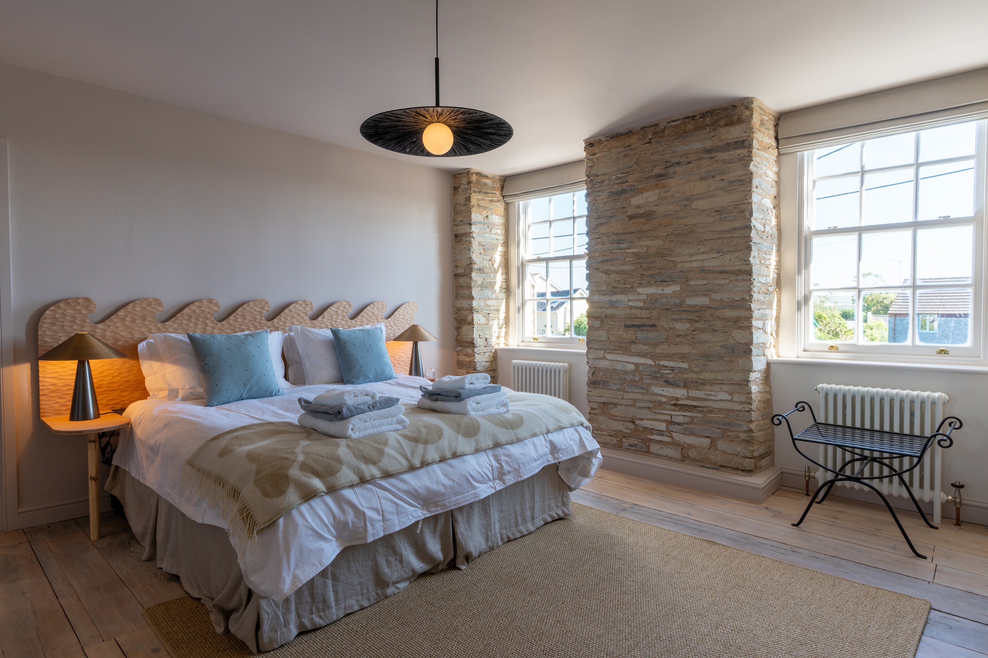 King-size bed decorated with throw pillows and blankets in a contemporary bedroom in Cornwall, England.