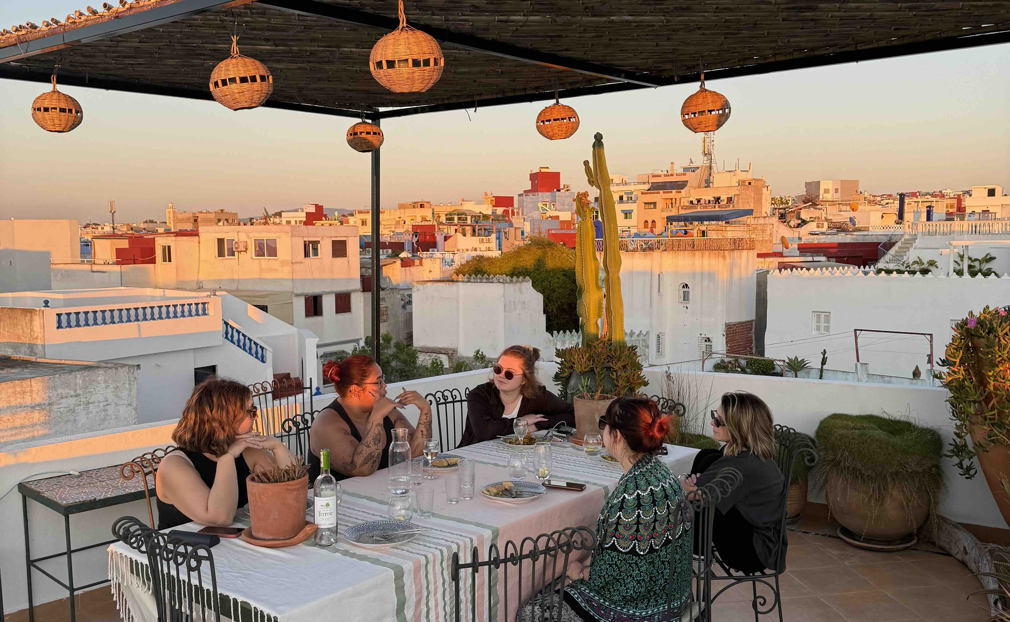 Sunset view from the rooftop of the Moroccan riad, picturing five women in discussion around a table.