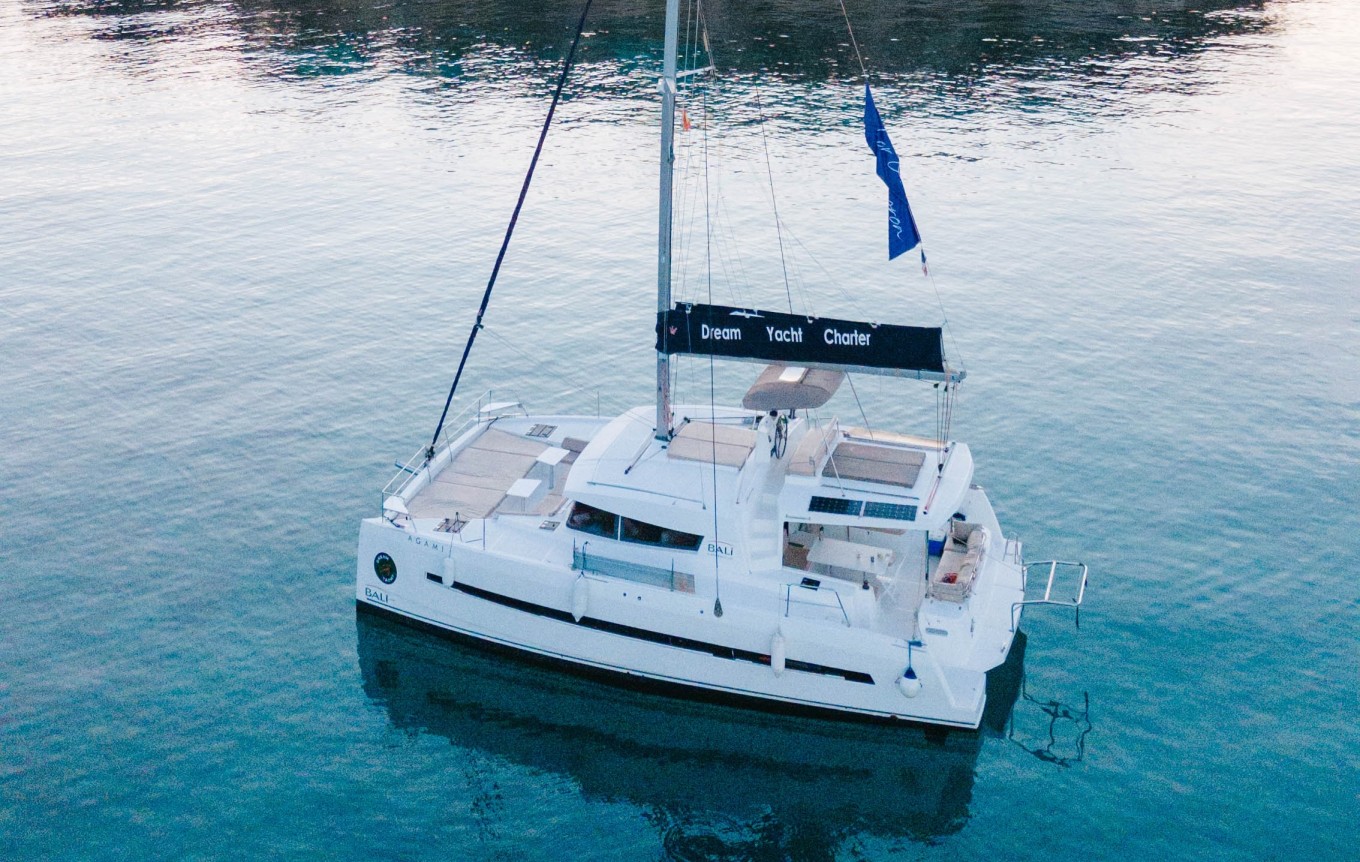 A luxury catamaran, anchored in crystal clear blue waters in Greece.