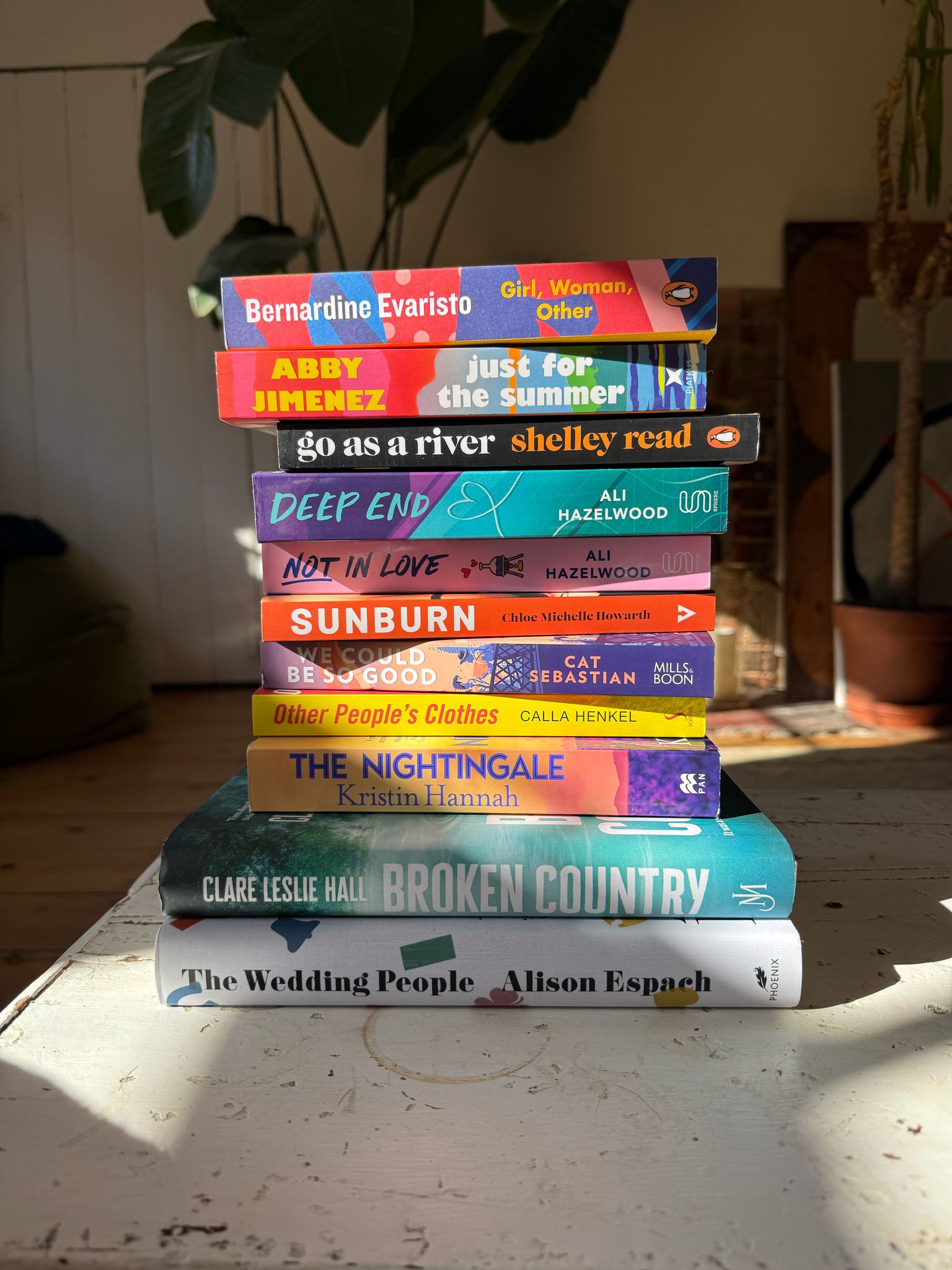 Stack of books in a living room highlighted by the sunlight.